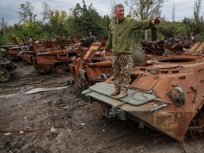 A Ukrainian serviceman stands on a destroyed Armoured Personnel Carrier (APC) in the town of Izium, recently liberated by Ukrainian Armed Forces, in Kharkiv region, Ukraine September 20, 2022.