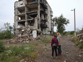 Women stand near a residential building destroyed by a military strike in the town of Izium recently liberated by the Ukrainian Armed Forces during a counteroffensive operation, amid Russia's attack on Ukraine, in Kharkiv region, Ukraine, Sept. 15, 2022.