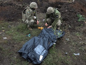 Ukrainian servicemen work with the body of their brother-in-arms exhumed at a former position of Ukrainian Armed Forces in the village of Kozacha Lopan, which was recently liberated during a counteroffensive operation, amid Russia's attack on Ukraine, near the Russian border in Kharkiv region, Ukraine, Sept. 16, 2022.
