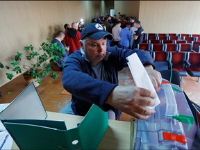 A man casts his ballot during a referendum on the secession of Zaporizhzhia region from Ukraine and its joining Russia, in the Russian-controlled city of Melitopol in the Zaporizhzhia region, Ukraine Sept. 26, 2022.