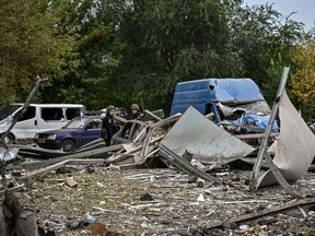 Ukrainische Polizisten kontrollieren am Freitag, den 30. September 2022, inmitten der russischen Invasion in der Ukraine, Autos, die durch einen Raketenangriff auf einer Straße in der Nähe von Saporischschja beschädigt wurden.
