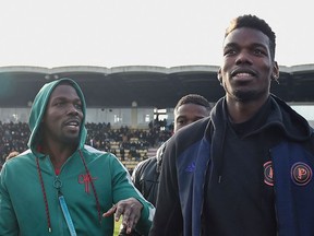 (FILES) This file photo taken on December 29, 2019 shows France national team player Paul Pogba (R) and his brother Mathias Pogba (L) walking on the pitch prior to a football match between All Star France and Guinea at the Vallee du Cher Stadium in Tours, central France, as part of the "48h for Guinea" charity event.