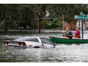 People paddle by in a canoe next to a submerged Chevy Corvette in the aftermath of Hurricane Ian in Orlando, Fla. on Sept. 29, 2022.