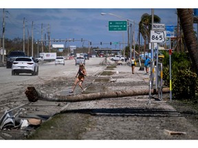 A woman crosses a street full of washed up mud in the aftermath of Hurricane Ian, in Fort Myers, Fla., Sept. 30, 2022.