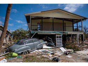 An old classic car sits in front of a house in the aftermath of Hurricane Ian, in Fort Myers, Fla., Sept. 30, 2022.