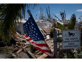 The U.S. flag waves as a pile of washed up boats are seen in the background in the aftermath of Hurricane Ian, in Fort Myers, Fla.