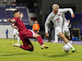 Qatar's Alrawi, left, tries tp stop Canada's Liam Millar during the international friendly soccer match between Qatar and Canada, at the Viola Park stadium in Vienna, Austria, Friday, Sept. 23, 2022.