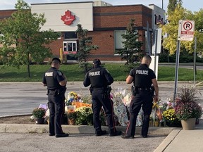 Peel Regional Police officers pay their respects to slain Toronto Police Const. Andrew Hong at a Tim Hortons in Mississauga on Friday, Sept. 16, 2022.