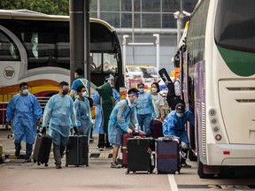 23 सितंबर, 2022 को होटल क्वारंटाइन में ले जाने से पहले कार्यकर्ता यात्रियों के सामान को हांगकांग अंतर्राष्ट्रीय हवाई अड्डे पर एक बस में लादते हैं।