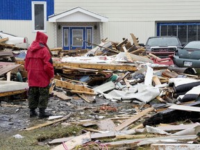 A Canadian Forces Ranger examines damage to a home in Port aux Basques, N.L., Monday, Sept. 26, 2022.
