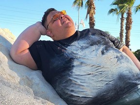 Israeli TikTok star Idan Ohayon leaning against a large pile of sand with palm trees in the background.
