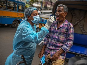 Health workers collect swab samples from commuters for COVID-19 coronavirus screening after a surge in number infections in Kolkata on July 4, 2022.