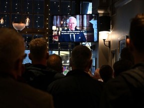 Drinkers in the Prince of Wales pub in central London watch a televised address by Britain's King Charles III, made from the Blue Drawing Room at Buckingham Palace in London on Sept. 9, 2022, a day after Queen Elizabeth II died at the age of 96.