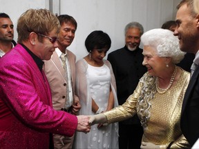 Queen Elizabeth II meets Sir Elton John backstage as British singer Robbie Williams, right, watches during the Diamond Jubilee Concert outside Buckingham Palace in London, on June 4, 2012.