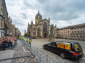 The hearse carrying the coffin of Queen Elizabeth II, draped in the Royal Standard of Scotland, is driven past St Giles' Cathedral in Edinburgh, en-route towards the Palace of Holyroodhouse, on September 11, 2022.