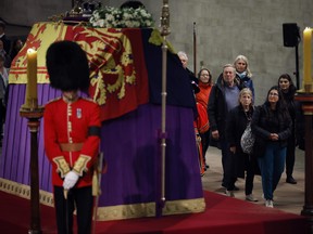 Members of the public file past Queen Elizabeth II's flag-draped casket lying in state on the catafalque as they enter Westminster Hall in the middle of the night on Sept. 17, 2022 in London.