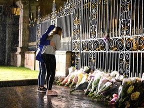 Women hold each other as they pause outside the gates at Hillsborough castle, Queen Elizabeth II's place of residence while visiting Northern Ireland, after Britain's longest-reigning monarch and the United Kingdom's figurehead for seven decades, died aged 96, at Royal Hillsborough, Northern Ireland Sept. 8, 2022.