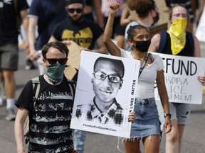 A demonstrator carries an image of Elijah McClain during a rally and march in Aurora, Colo., June 27, 2020.