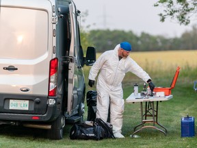 An investigator in protective equipment takes a tool off the table at a crime scene in Weldon, Sask., on Sunday, Sept. 4, 2022.
