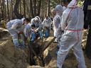 Rescue workers and forensic police exhume bodies from unidentified makeshift graves at the Pishanske cemetery on September 21, 2022 in Izium, Ukraine. 