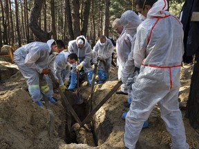 Rescue workers and forensic police exhume bodies from unidentified makeshift graves at the Pishanske cemetery on September 21, 2022 in Izium, Ukraine.