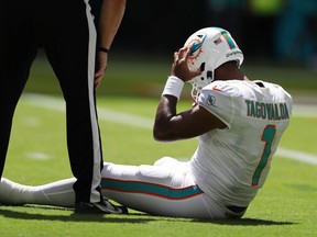 Quarterback Tua Tagovailoa of the Miami Dolphins sits on the turf during a game against the Buffalo Bills.