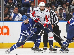 Erik Gustafsson of the Washington Capitals battles against Denis Malgin of the Toronto Maple Leafs during an NHL game at Scotiabank Arena on October 13, 2022 in Toronto, Ontario, Canada.