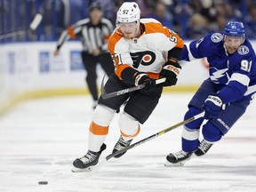 Wade Allison #57 of the Philadelphia Flyers and Steven Stamkos #91 of the Tampa Bay Lightning fight for the puck during a game  at Amalie Arena on October 18, 2022 in Tampa, Florida.