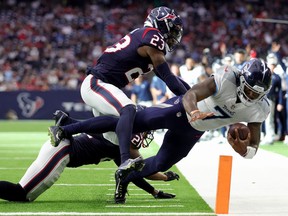 Malik Willis #7 of the Tennessee Titans is tackled by Eric Murray #23 and Steven Nelson #21 of the Houston Texans during the third quarter at NRG Stadium on October 30, 2022 in Houston, Texas.
