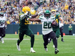 Breece Hall of the New York Jets avoids a tackle from Kingsley Enagbare of the Green Bay Packers before scoring a touchdown.