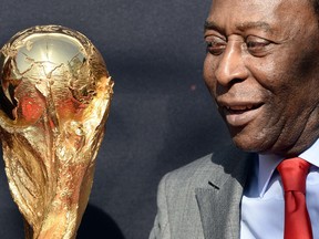 Brazilian football legend Pele looks at the FIFA World Cup trophy during a FIFA event on March 9, 2014 outside the Hotel de Ville in Paris.