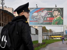 A military cadet stands in front of a billboard promoting contract army service in St. Petersburg on Oct. 5, 2022.