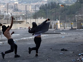 A Palestinian woman throws a Molotov cocktail towards Israeli security forces as another hurls rocks, during confrontations with them in the Shuafat refugee camp in Israeli-annexed east Jerusalem, on October 12, 2022.