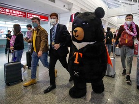 A mascot and an official (centre left) welcome a group of passengers from Thailand at Taoyuan International Airport in Taoyuan on October 13, 2022, after Taiwan reopened its borders by ending mandatory COVID quarantine for arrivals.