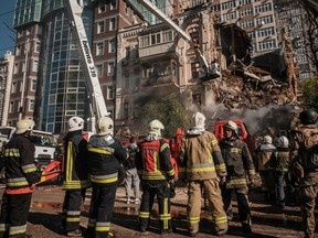 Ukrainian firefighters works on a destroyed building after a drone attack in Kyiv on October 17, 2022, amid the Russian invasion of Ukraine (Photo by YASUYOSHI CHIBA/AFP via Getty Images)