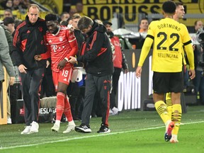Bayern Munich's Canadian midfielder Alphonso Davies (second from left) reacts injured on the sidelines during the German first division Bundesliga football match between BVB Borussia Dortmund and FC Bayern Munich in Dortmund, western Germany, on Oct. 8, 2022.
