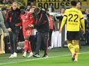 Bayern Munich's Canadian midfielder Alphonso Davies (second from left) reacts injured on the sidelines during the German Bundesliga first division soccer match between BVB Borussia Dortmund and FC Bayern Munich in Dortmund, western Germany, October 8, 2022.