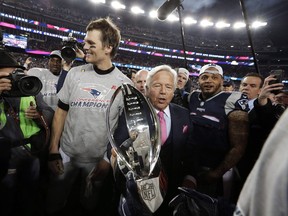 New England Patriots owner Robert Kraft, center, carries the trophy with his team's then quarterback Tom Brady as they leave the field after the 2018 AFC championship game.
