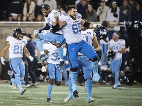 Dariusz Bladek (65) and Argonauts players react after defeating the Montreal Alouettes in Montreal, Saturday, October 22, 2022.
