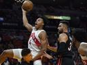 Toronto Raptors forward Scottie Barnes (4) drives to the basket over Miami Heat guards Tyler Herro and guard Max Strus (31) during the first half in Miami on Saturday night. Barnes rolled his ankle on the play. 
