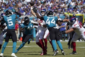 New York Giants quarterback Daniel Jones is pressured by Jacksonville Jaguars linebacker Travon Walker (44) as he throws a pass during the first half of an NFL football game Sunday, Oct. 23, 2022, in Jacksonville, Fla. (AP Photo/John Raoux)