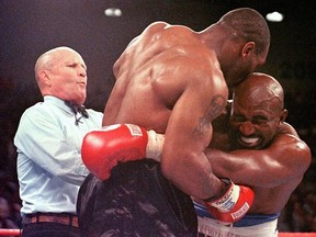 Referee Lane Mills (L) steps in as Evander Holyfield (R) reacts after Mike Tyson (C) bit his ear in the third round of their WBA Heavyweight Championship Fight at the MGM Grand Garden Arena in Las Vegas June 28, 1997.