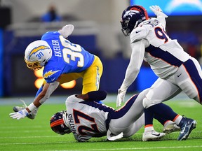 Los Angeles Chargers running back Austin Ekeler (30) is brought down by Denver Broncos cornerback Damarri Mathis (27) and Denver Broncos defensive tackle DeShawn Williams (99) during the first half at SoFi Stadium on Oct. 17, 2022.