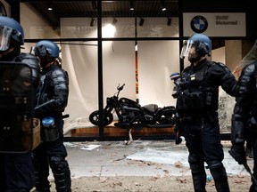 French gendarmes secure a destroyed BMW shop window during clashes at a demonstration in Paris as part of a nationwide day of strike and protests for higher wages and against requisitions at refineries in France, Oct. 18, 2022.