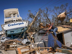 People clear debris in the aftermath of Hurricane Ian in Fort Myers Beach, Fla., Friday, Sept. 30, 2022.