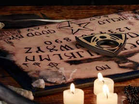 Ouija Board with candles. Seance on wooden table. The mystical atmosphere of the call of spirits. Black magic.