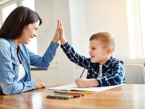 A mother and son exchange a high-five while going over homework.