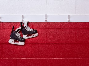 Hockey skates hanging over red wall in locker room with copy space