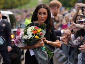 Meghan, Duchess of Sussex, collects flowers as she chats with well-wishers on the Long walk at Windsor Castle on Sept. 10, 2022, two days after the death of Britain's Queen Elizabeth II at the age of 96.