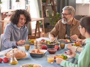 Happy family talking to each other while sitting at the table and having dinner at home